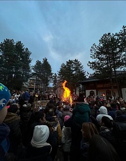Scenografija Badnje večeri na Zlatiboru sa okićenom crkvom i velikim plamenom božićne jelke koji grije okupljene vjernike