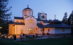 Veličanstvena arhitektura Hrama Preobraženja Gospodnjeg na Zlatiboru noću pod profesionalnim dekorativnim osvjetljenjem koje ističe bijele fasadne zidove i konture crkve u kontrastu s tamnim planinskim nebom i osvijetljenim okolnim stazama