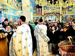 Дубок и емотиван приказ најмлађих верника у порти храма на Златибору током прославе дечијег празника Врбица. Група деце различитог узраста носи исплетене венчиће од освећених врбових гранчица на главама и карактеристичне звончиће на тробојкама око врата. Деца су одевена у празничну гардеробу, а у рукама држе свежњеве врбице, симболишући поздрав Христу при уласку у Јерусалим. У позадини се назиру родитељи и остали парохијани златиборске цркве Преображења Господњег, стварајући топлу породичну и верску атмосферу. Фотографија је одличан приказ локалних обичаја и верског туризма на Златибору.