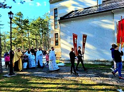 Свечана празнична литија за Врбицу (Лазареву суботу) 2026. године у порти Храма Преображења Господњег на Златибору. На снимку се види дуга колона деце са звончићима и верника која пролази поред карактеристичних златиборских борова. На челу поворке су црквени барјаци са иконама. Овај кадар документује верски живот златиборске парохије и традиционално окупљање народа и туриста током Васкршњег поста.