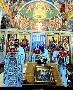 Veliki vhod tokom Svete Liturgije na Cveti u hramu Svetog Preobraženja Gospodnjeg na Zlatiboru 6. aprila 2026. godine. Protojerej Miodrag Todorović nosi časni putir, a starešina hrama protojerej Dejan Vojisavljević i đakon Nenad Srećković učestvuju u svečanom liturgijskom vhodu kroz naos ispunjen vernicima. Sveštenoslužitelji su u prazničnim belim odeždama, prolazeći pored ikone Ulaska Gospodnjeg u Jerusalim ukrašene zlatiborskim cvećem. Fotografija dokumentuje ključni momenat bogosluženja u hramu Svetog Preobraženja Gospodnjeg pod kupolama koje krase čuvene zlatiborske freske i raskošni polijeleji